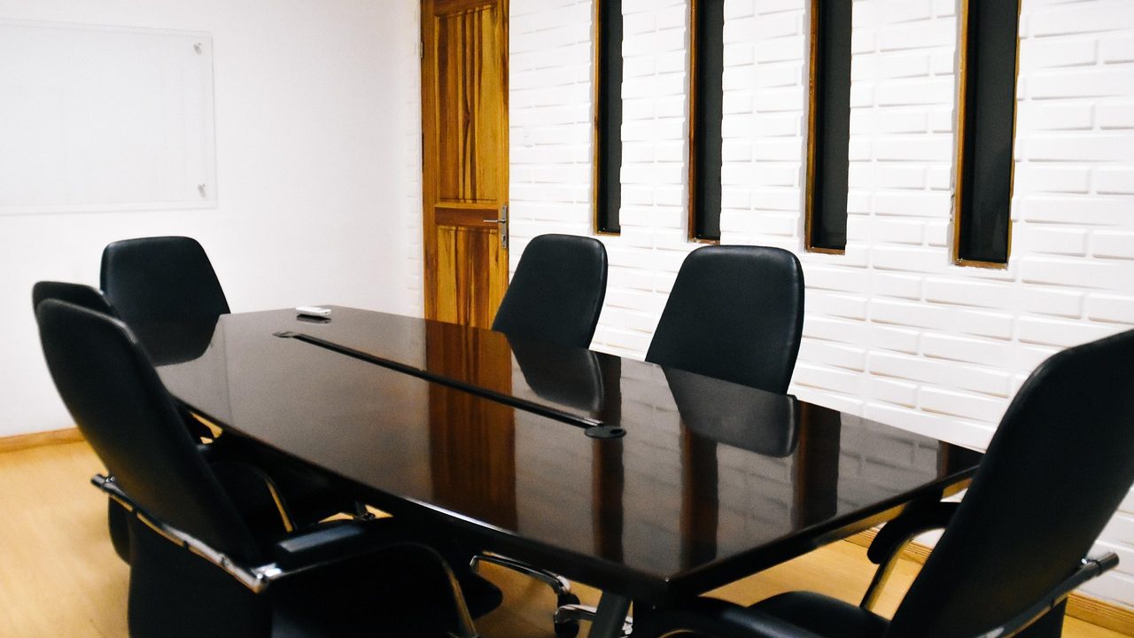 An empty corporate conference room with chairs around a long table.