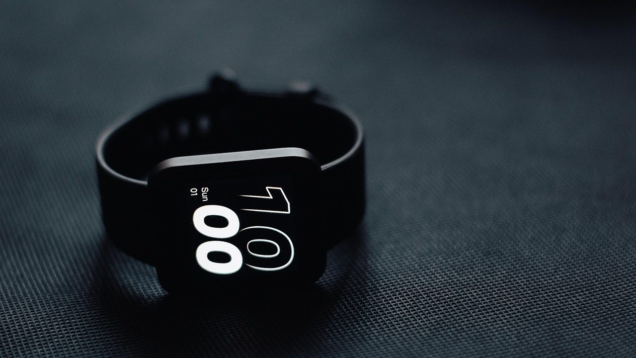 A modern smartwatch on a wrist displaying a glowing digital interface.