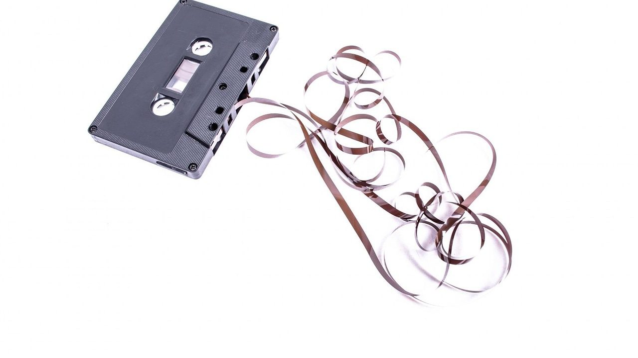A vintage reel-to-reel magnetic tape recorder with two large spools on a wooden surface.