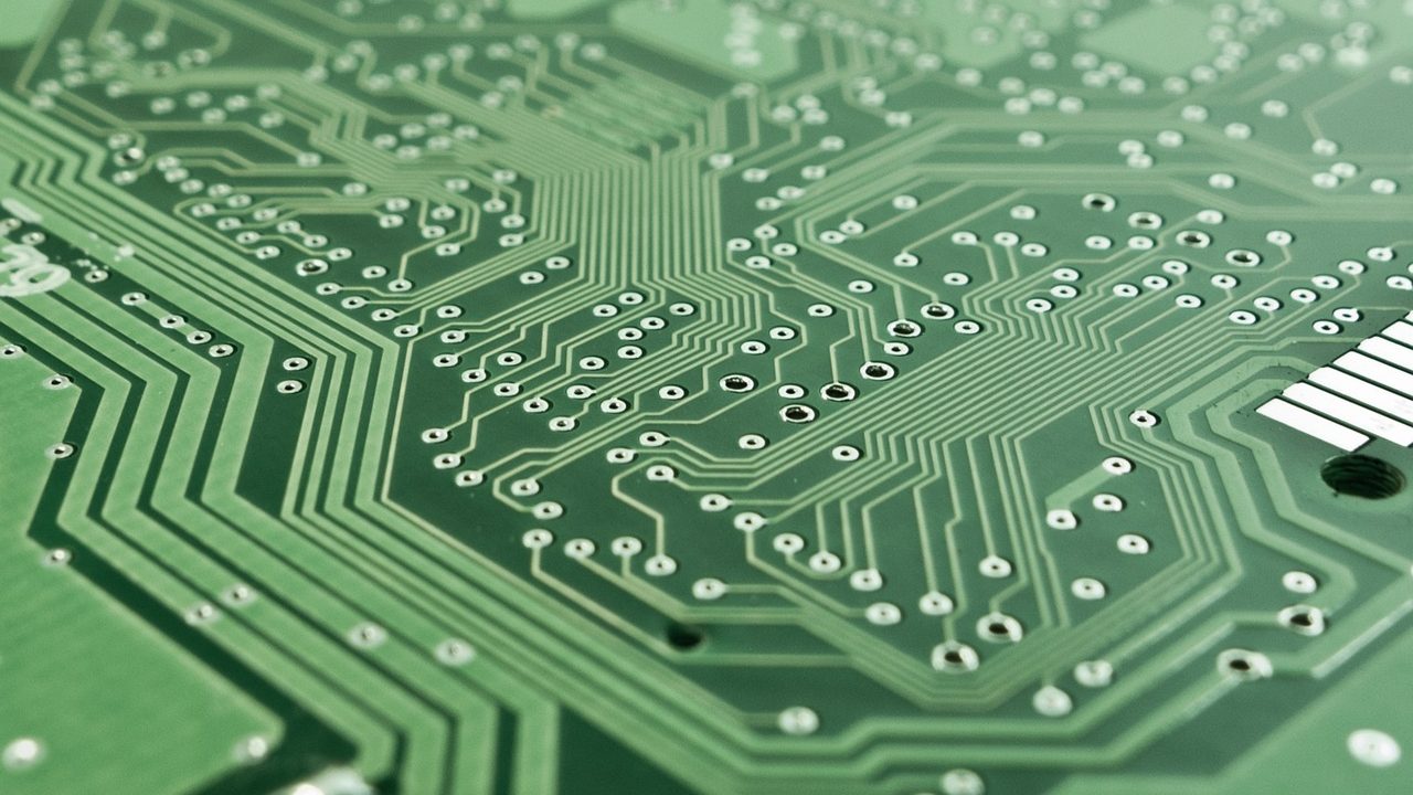 Close-up photograph of green printed circuit board with copper traces and chips.