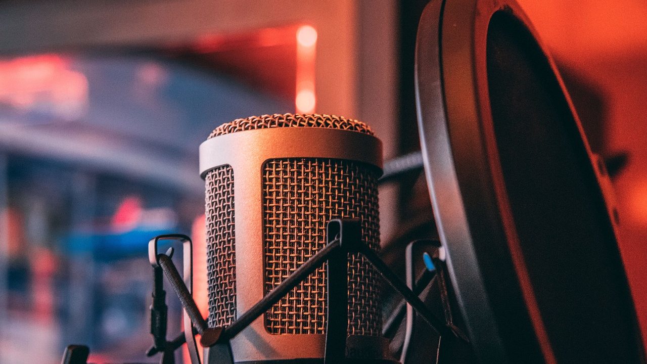 Two microphones on a desk in a professional podcast recording studio.