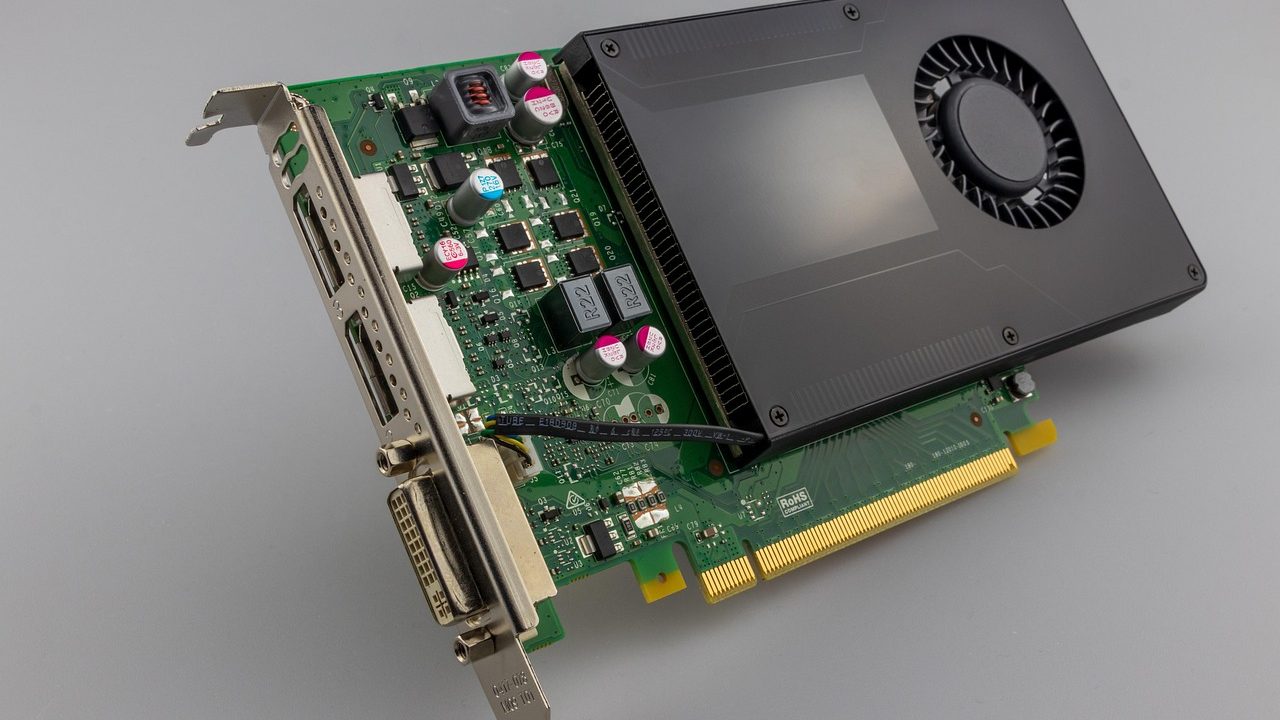 A graphics processing unit circuit board with cooling fans against a dark background.