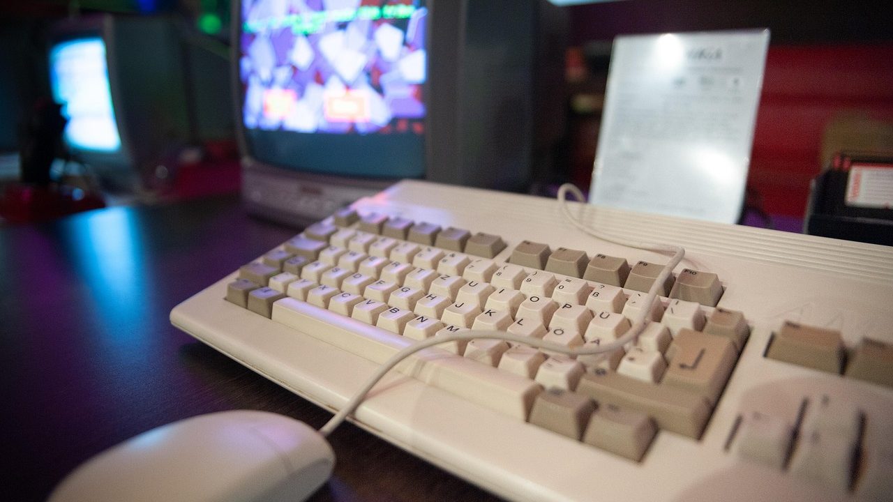 An old cathode-ray tube computer monitor and keyboard on a wooden desk.