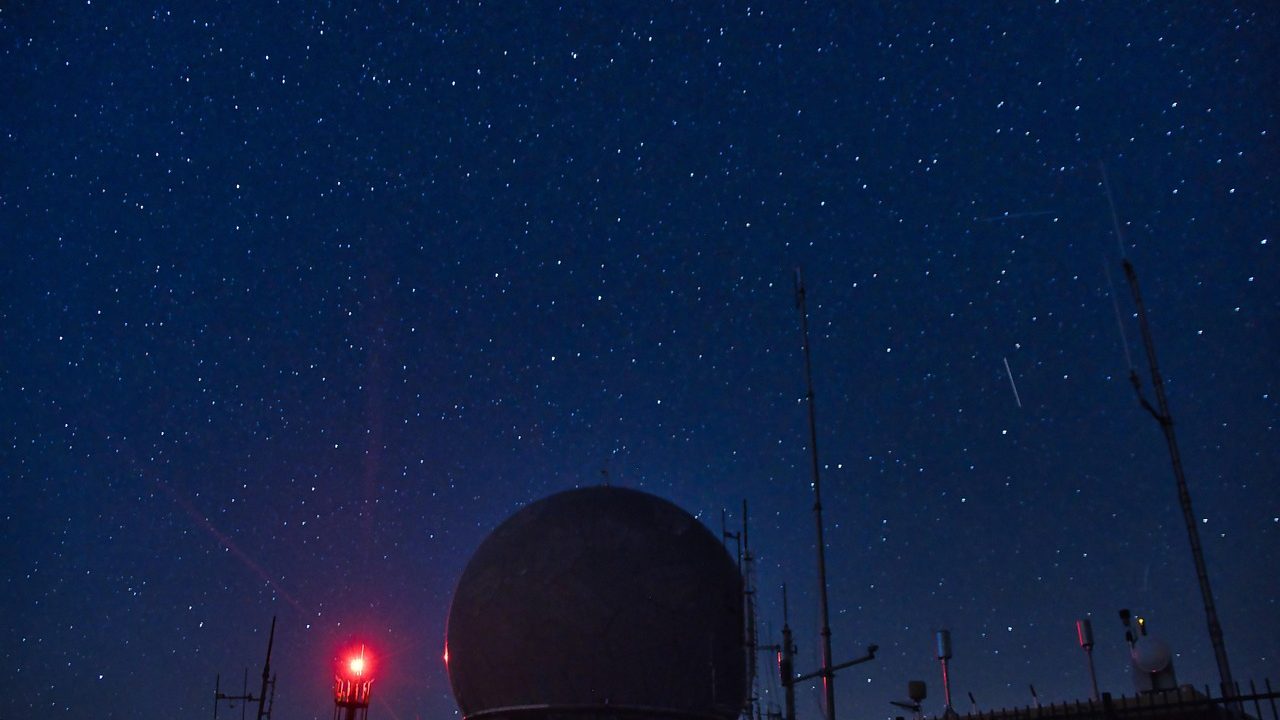 A large astronomical observatory dome open at night under a star-filled sky.