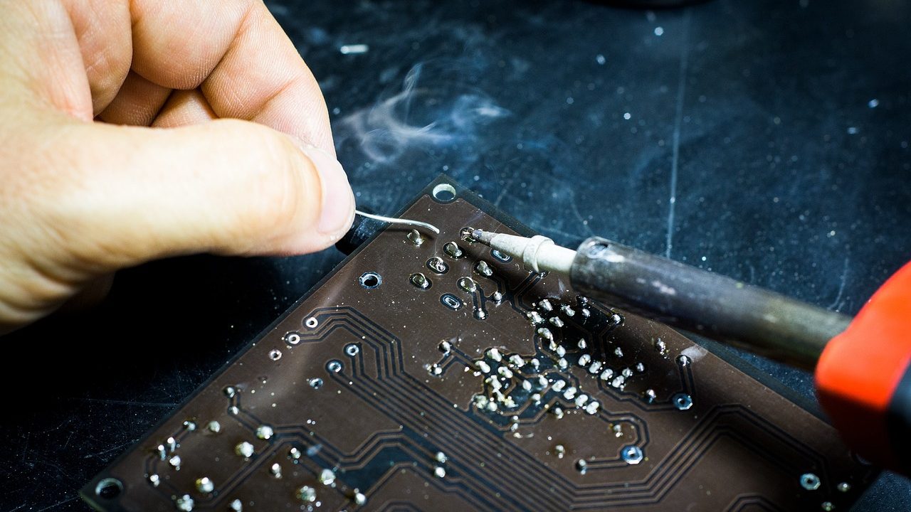 A technician's workbench covered with small electronic components, screwdrivers, and circuit boards.