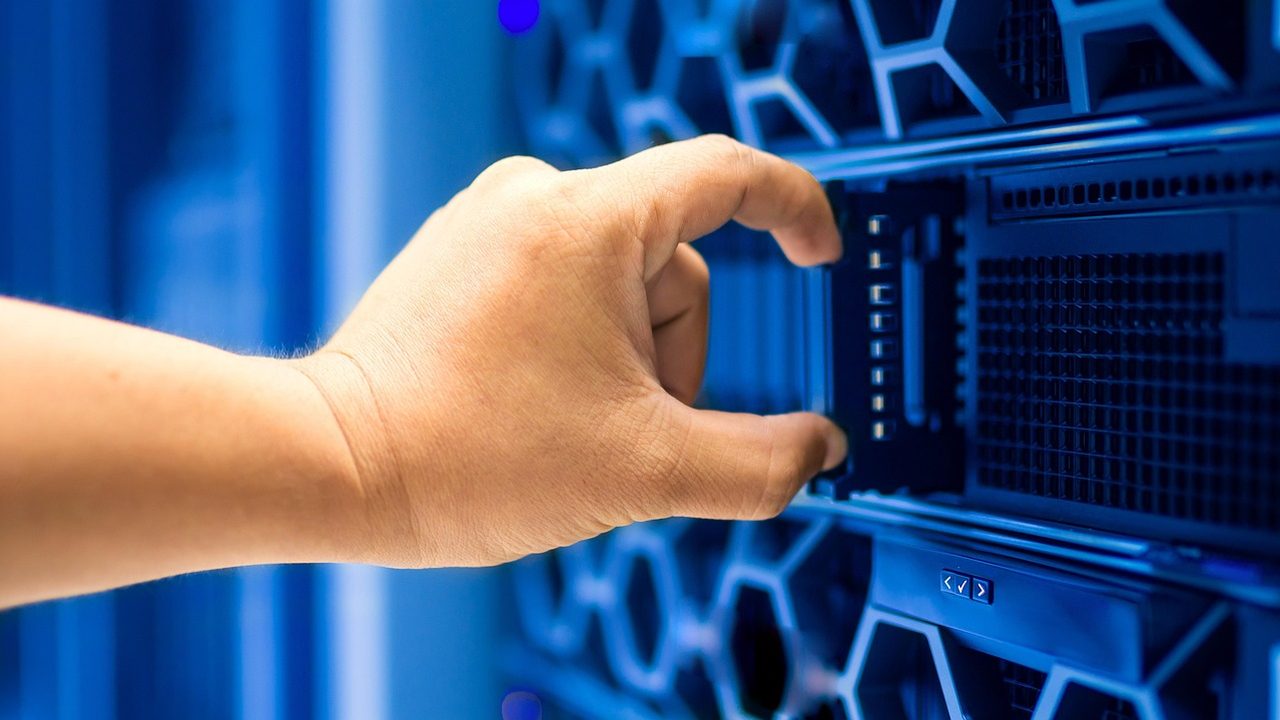 Rows of illuminated server racks inside a large data center facility.