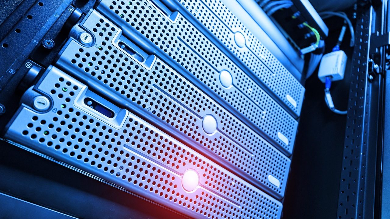 A rack of illuminated servers with blinking status lights in a darkened data center.