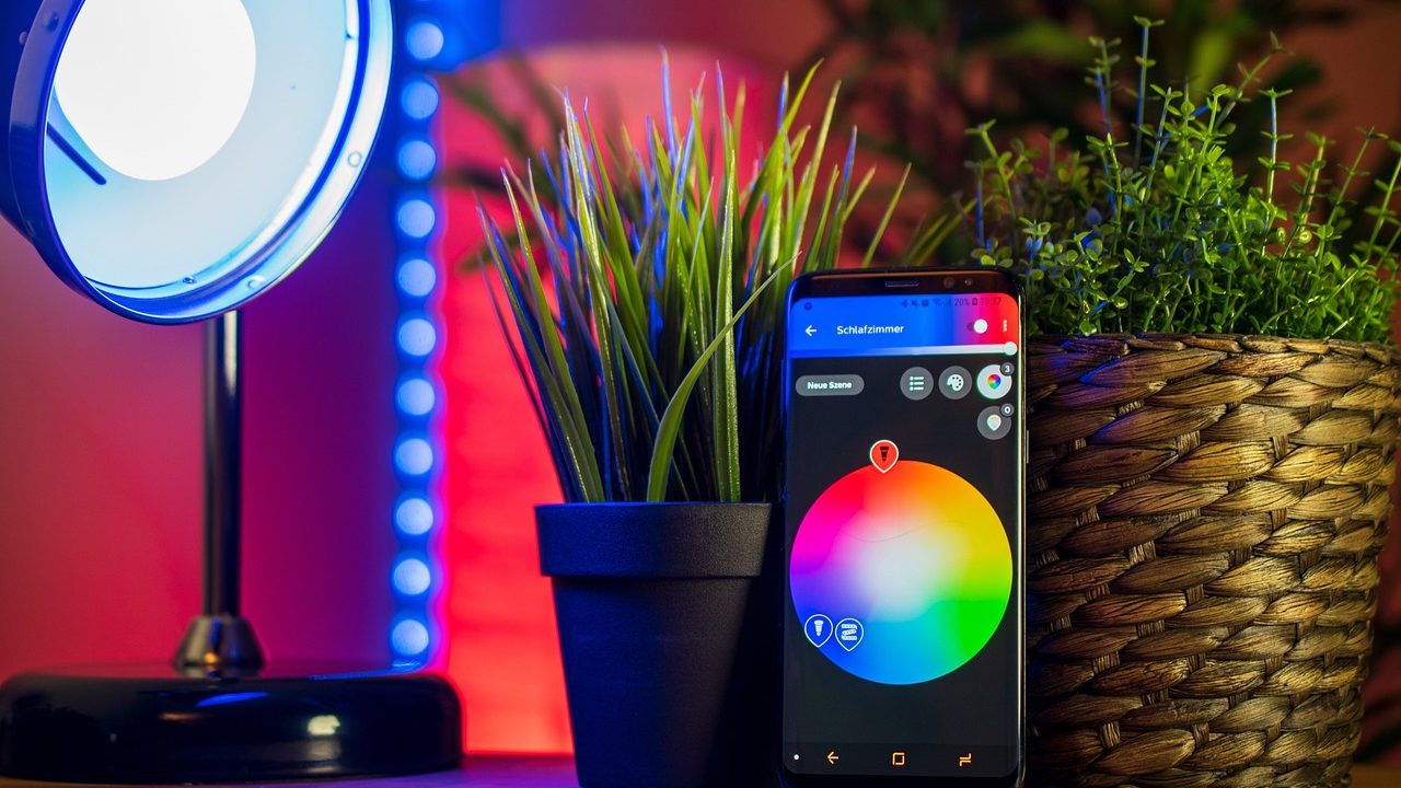 A white wireless router and smart home hub on a shelf with indicator lights glowing.