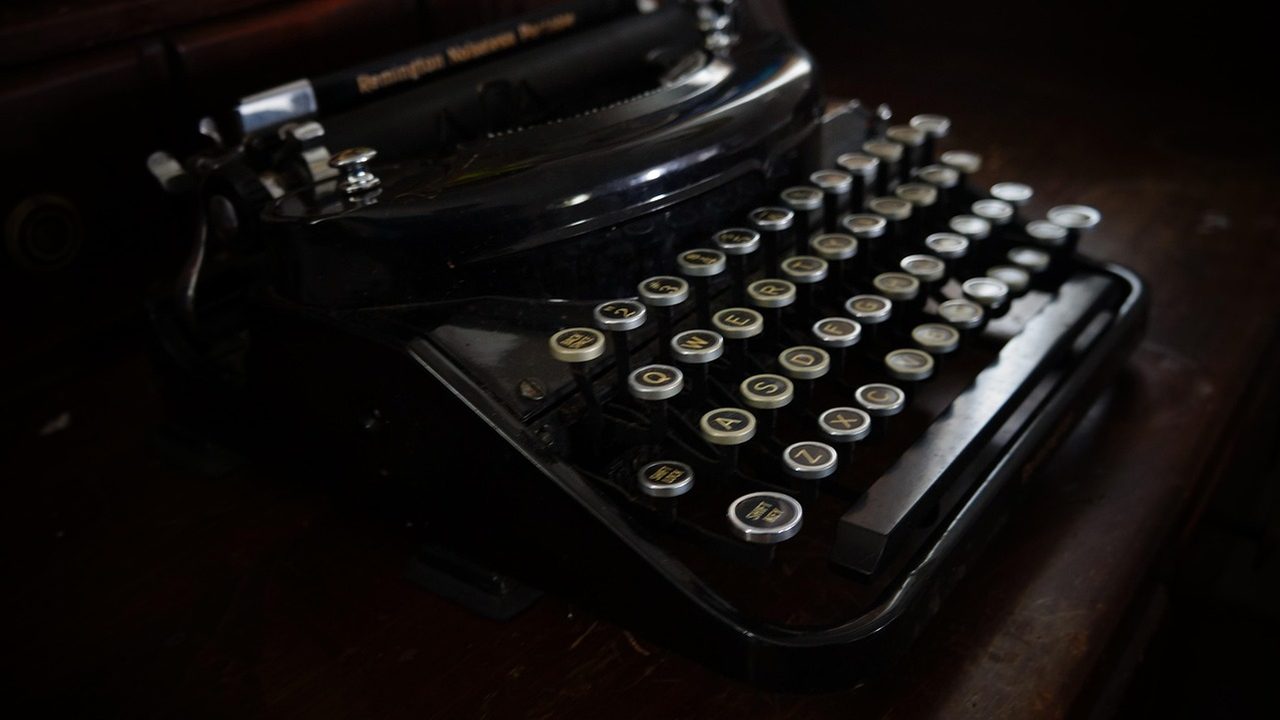 A retro personal computer with a chunky beige keyboard and old-style monitor on a wooden desk.