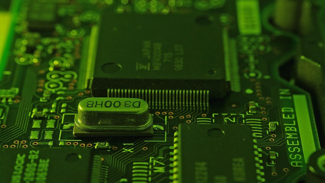 Extreme close-up of a green circuit board with copper traces and mounted components.