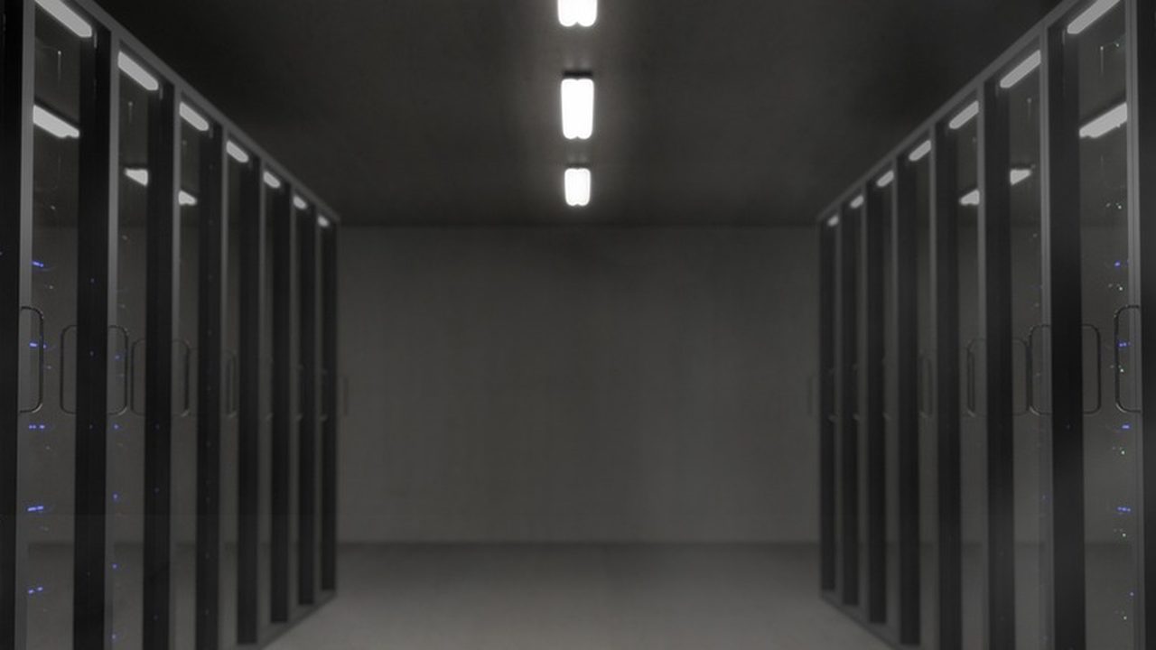 Rows of illuminated servers in a dark data center with blue ambient lighting.