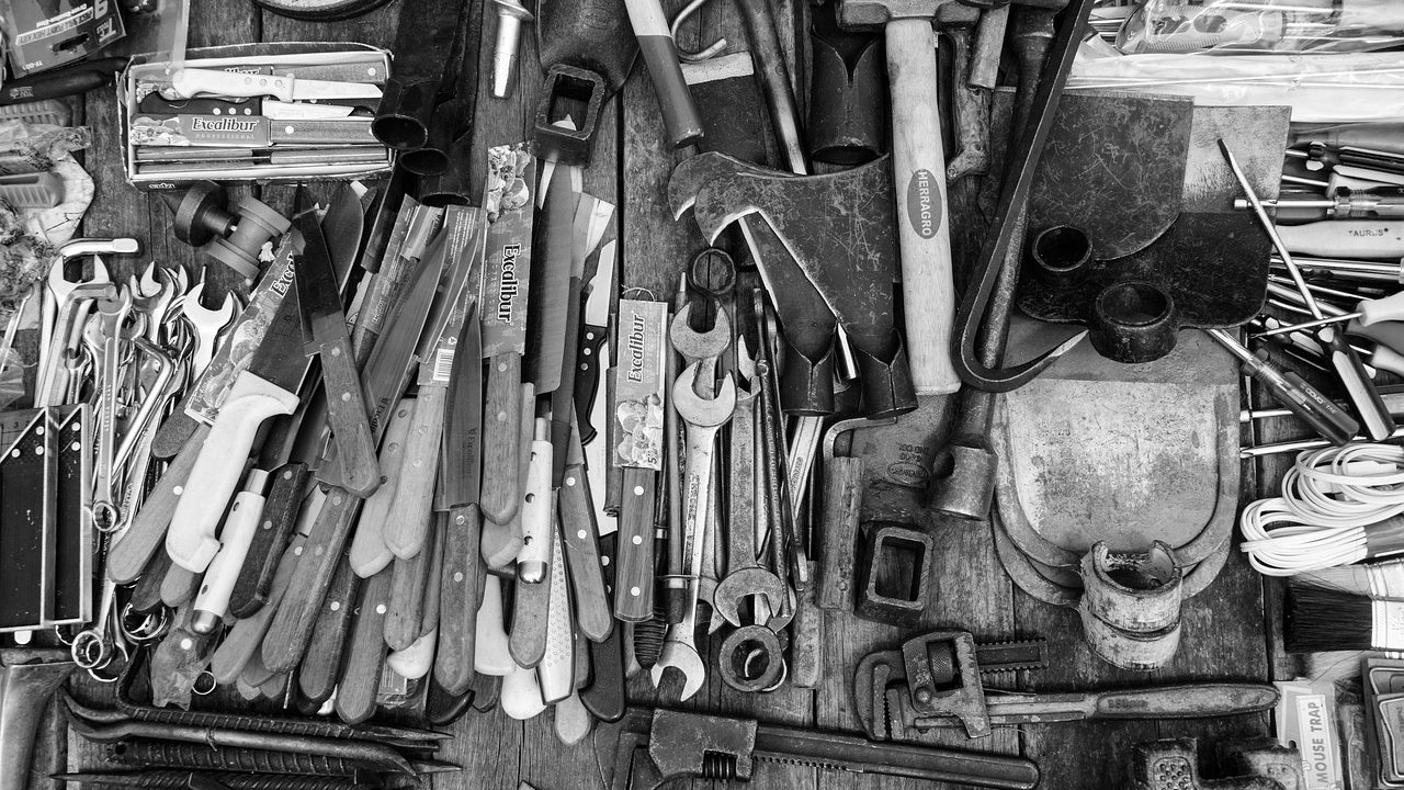 Workbench covered with disassembled electronic devices, tools, and component parts under bright lighting.