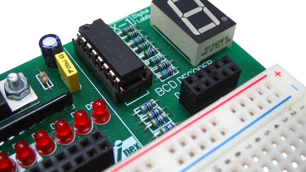 A small e-ink display resting on a cluttered electronics workbench surrounded by components.