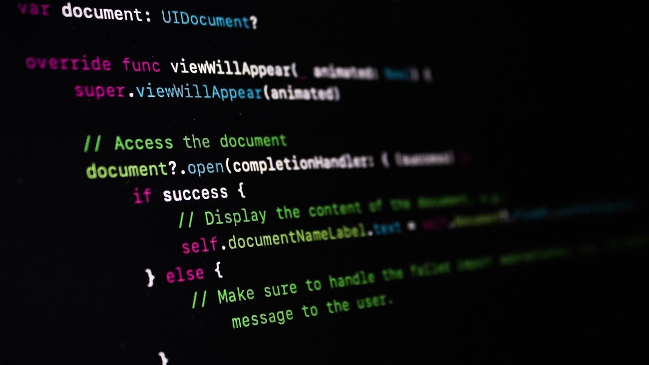 A laptop screen displaying colorful lines of source code in a dark-themed code editor.