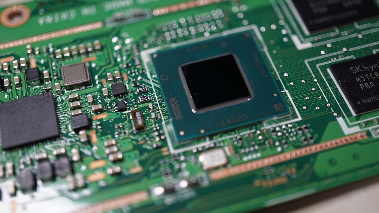 A close-up photograph of a green circuit board with gold processor contacts.