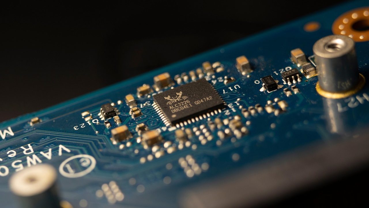 A close-up of a green circuit board covered in microchips and copper traces.