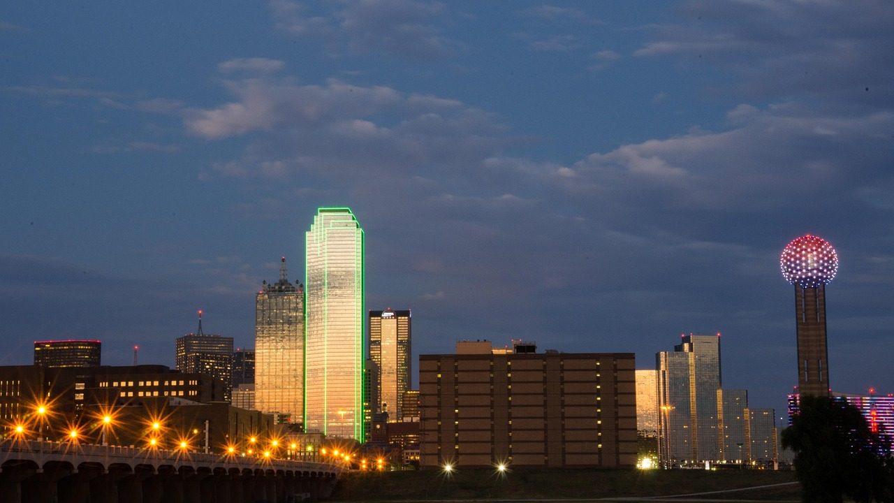 Glass skyscrapers rise against a clear sky in a major Texas city's downtown district.
