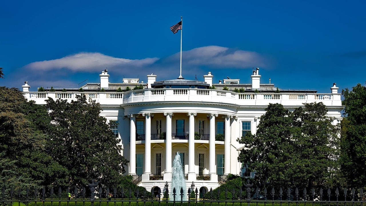 The White House exterior with classical columns visible against a clear sky.