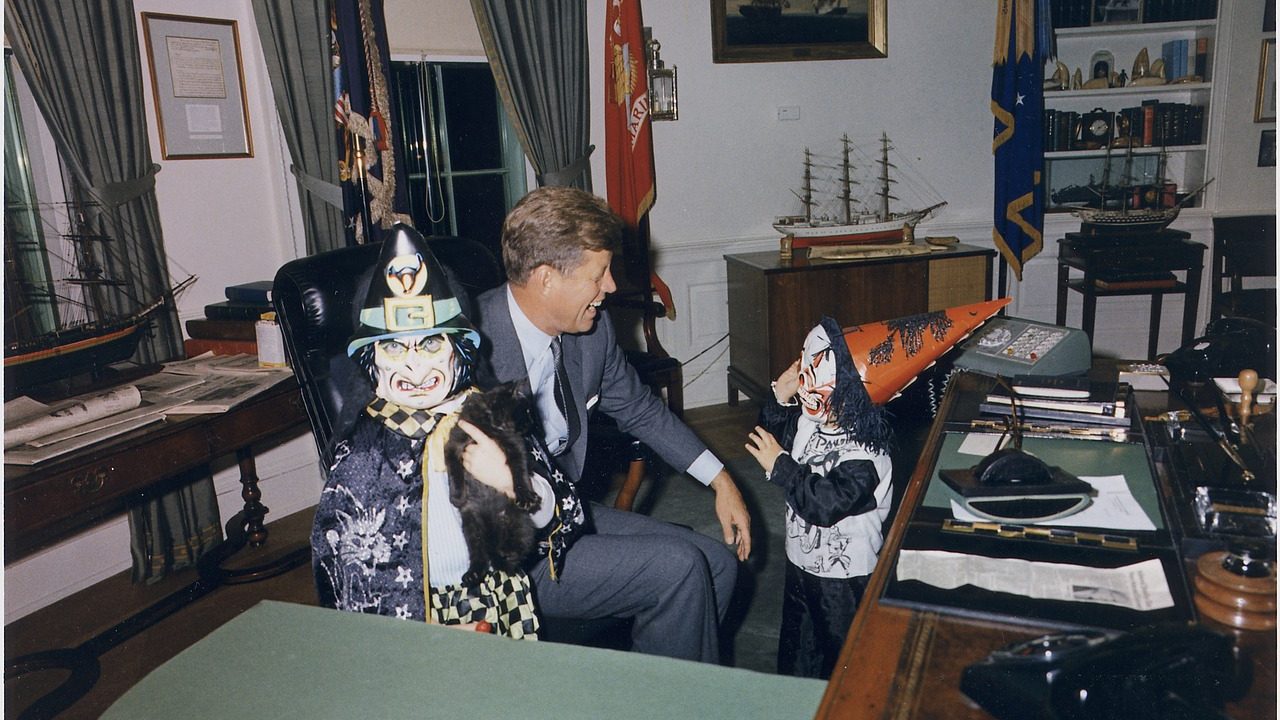 The Oval Office desk sits beneath flags in the White House.
