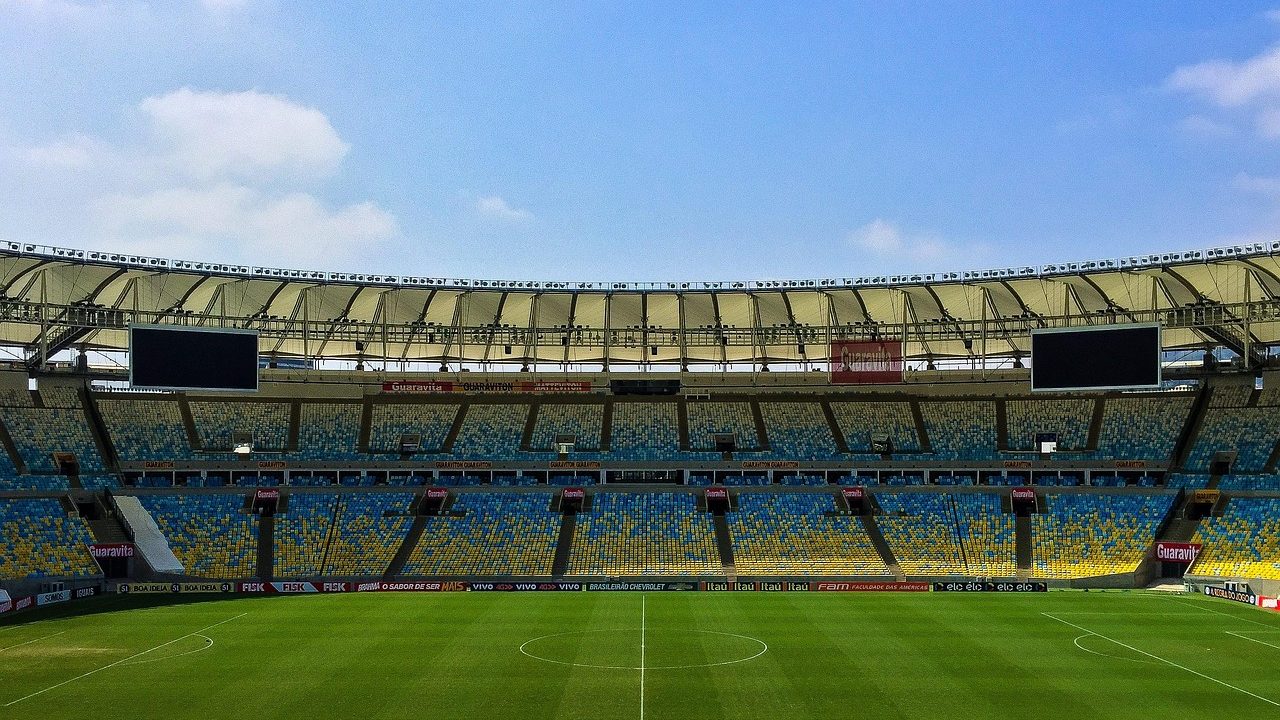 An aerial view of a packed soccer stadium with green field below.