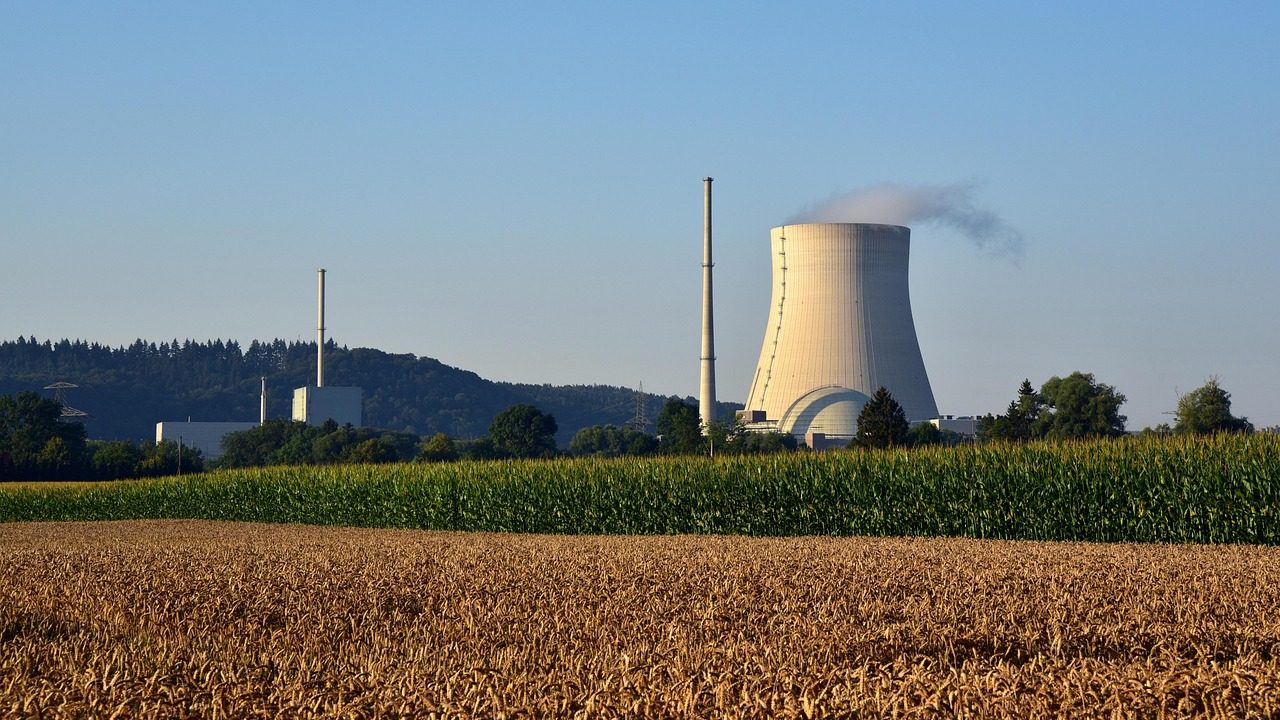 Large concrete cooling towers at a nuclear facility reflected in a still water reservoir.