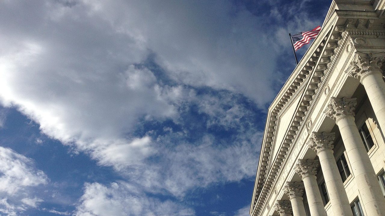 Stone columns of a large government building stand against a partly cloudy sky.