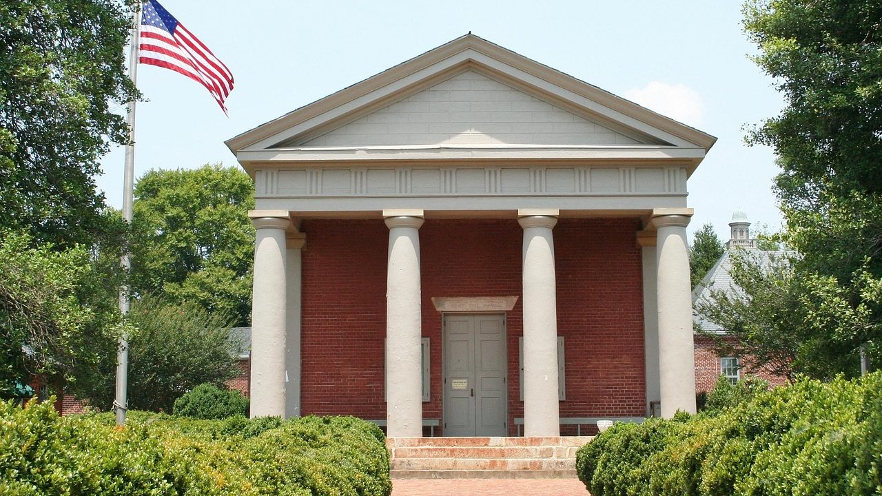 Tall marble columns on the exterior of a federal courthouse under clear blue sky.