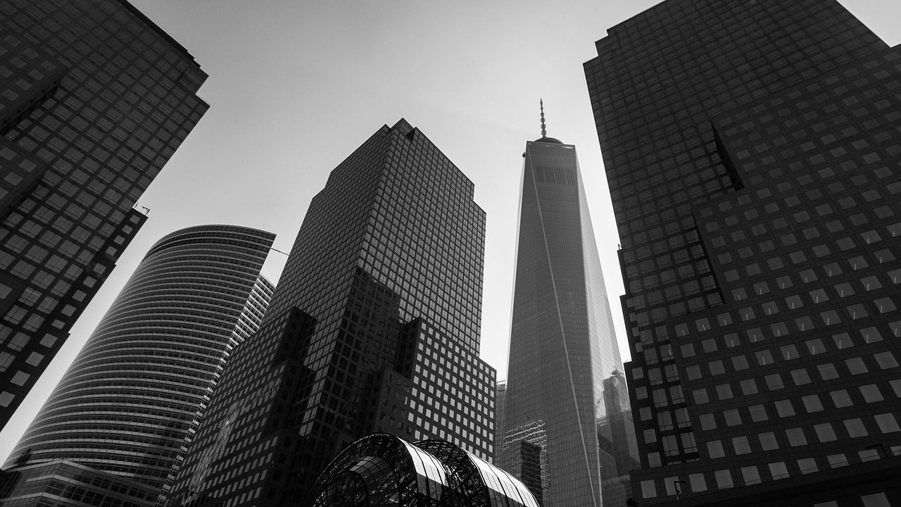 Glass skyscrapers in a financial district reflecting sunlight against a blue sky.