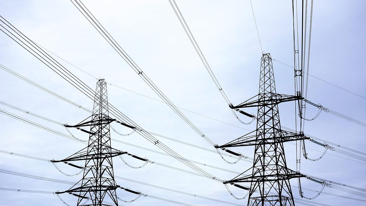 High-voltage electrical transmission towers and power lines crossing open countryside.