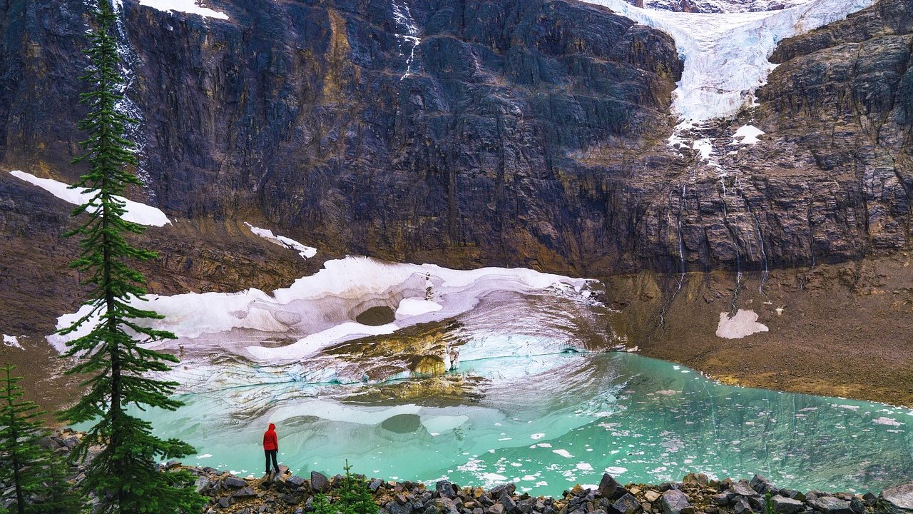 A retreating mountain glacier with exposed dark rock visible along its receding edges.