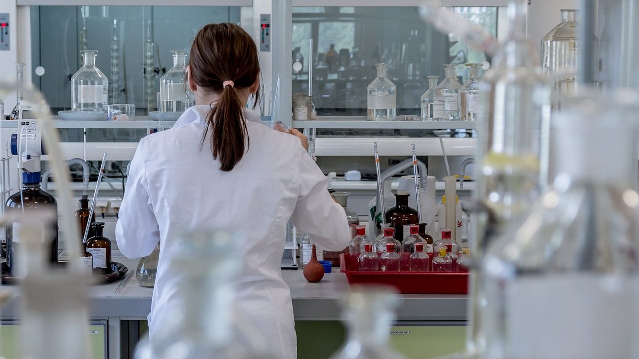 Scientists in a laboratory observing glowing plasma contained within experimental research equipment.