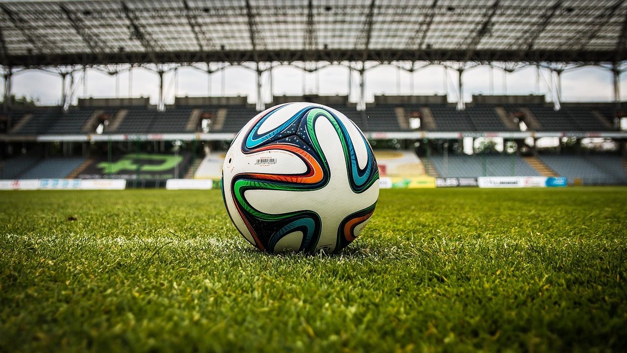 An empty professional soccer stadium with green turf and bright floodlights.