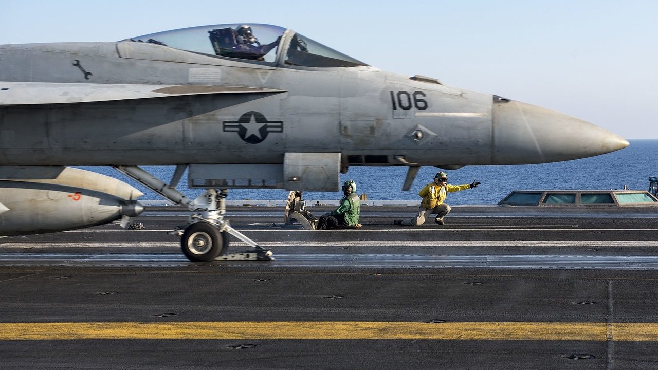 Fighter jets parked on the deck of a military aircraft carrier at sea.