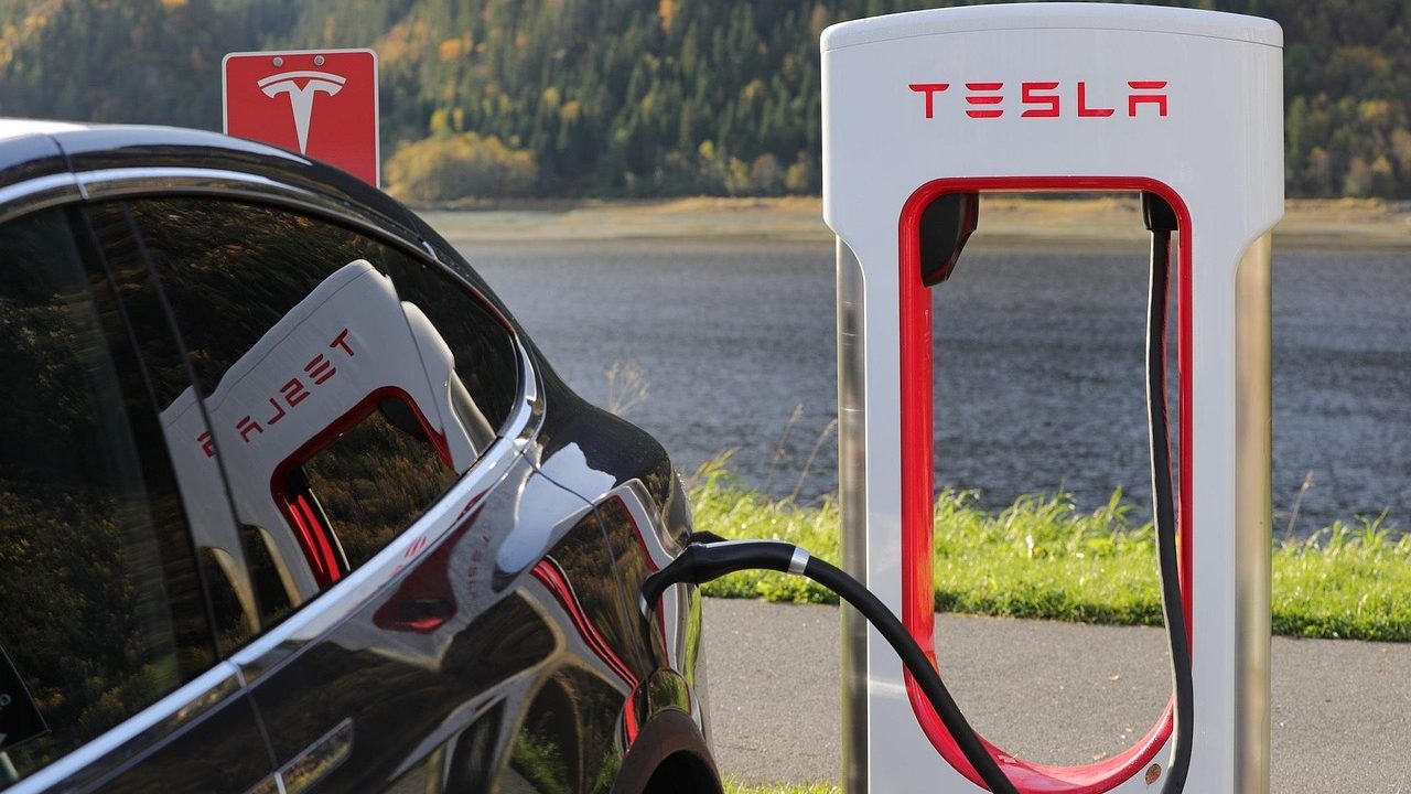 Electric vehicles plugged into charging stations in an outdoor parking area.