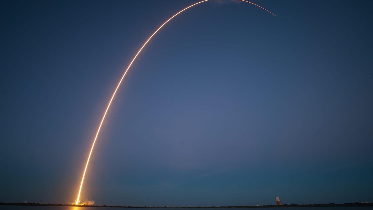A large rocket illuminated by floodlights on a launch pad at night before liftoff.