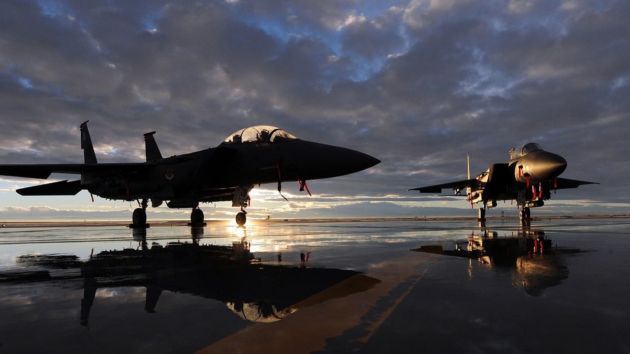 A military fighter jet sits on a tarmac at an air base during daylight.