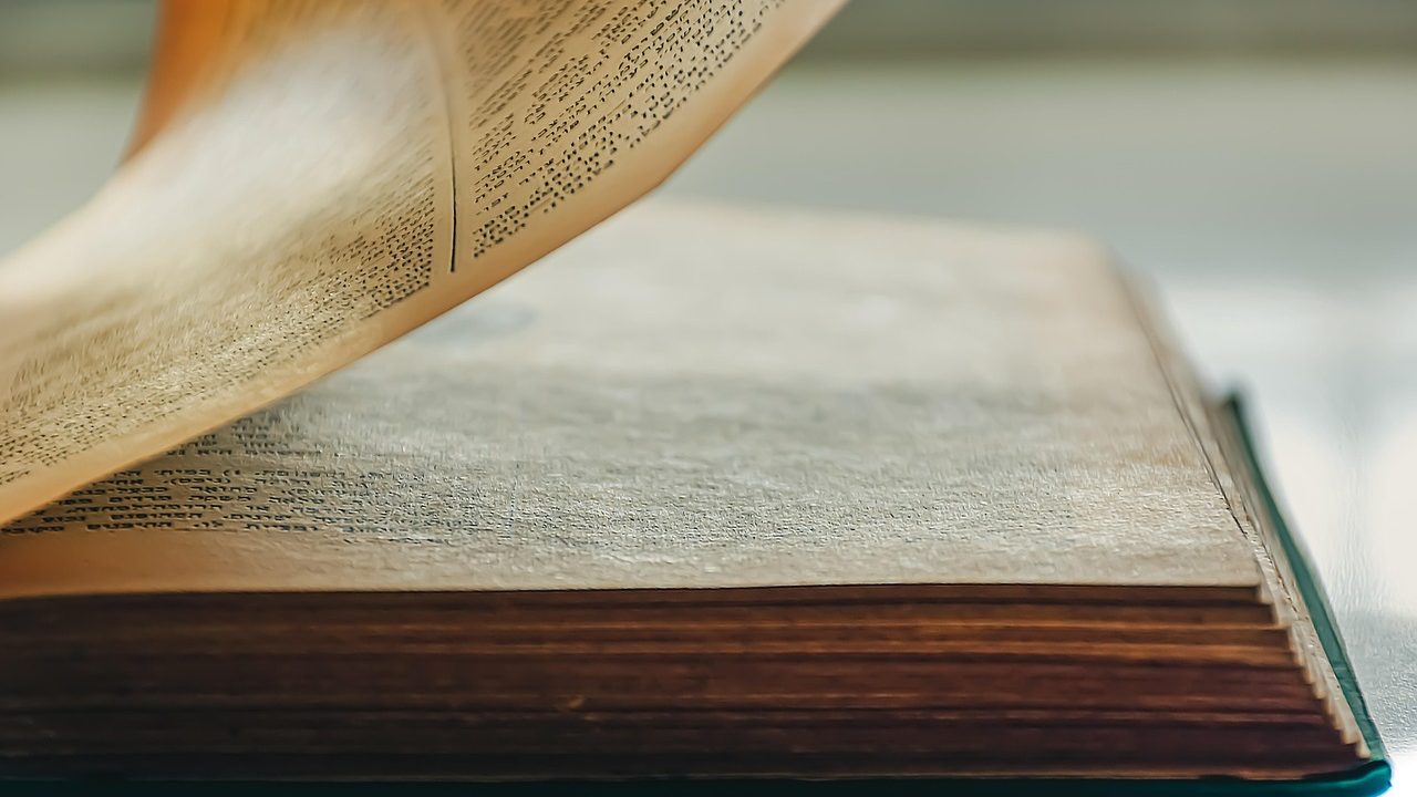 Close-up of printed manuscript pages spread open on a wooden desk.