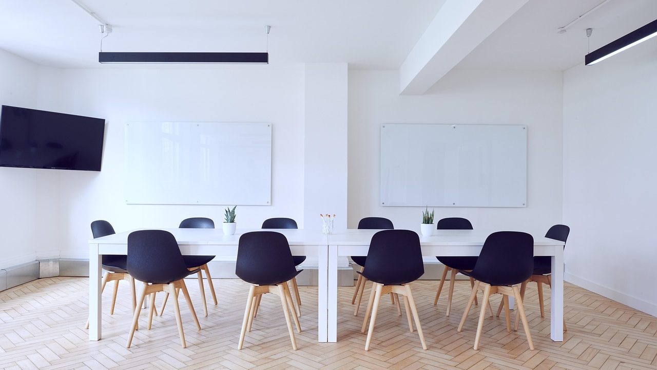 An empty conference table with chairs and water glasses in a formal negotiating room.