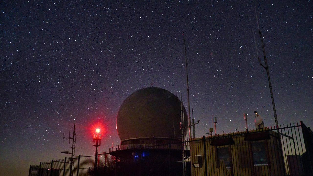 A large observatory telescope dome silhouetted against a star-filled night sky.