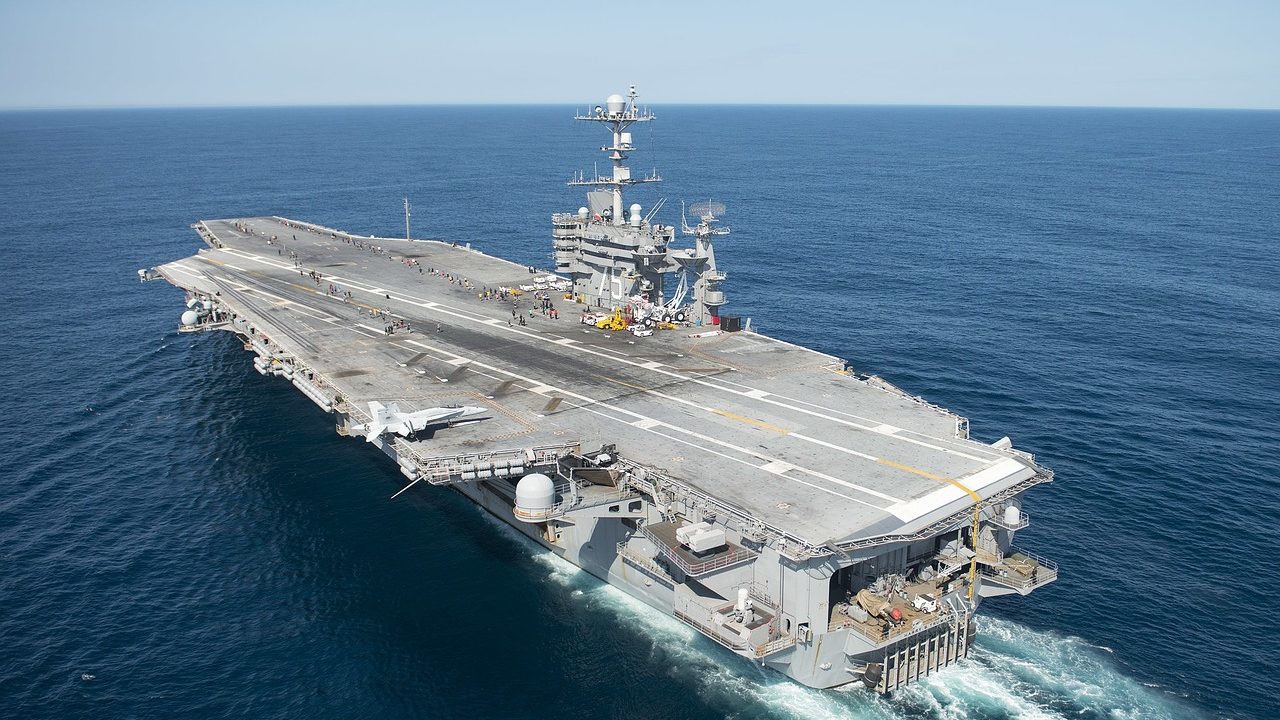 The flight deck of a large aircraft carrier at sea under a clear sky.