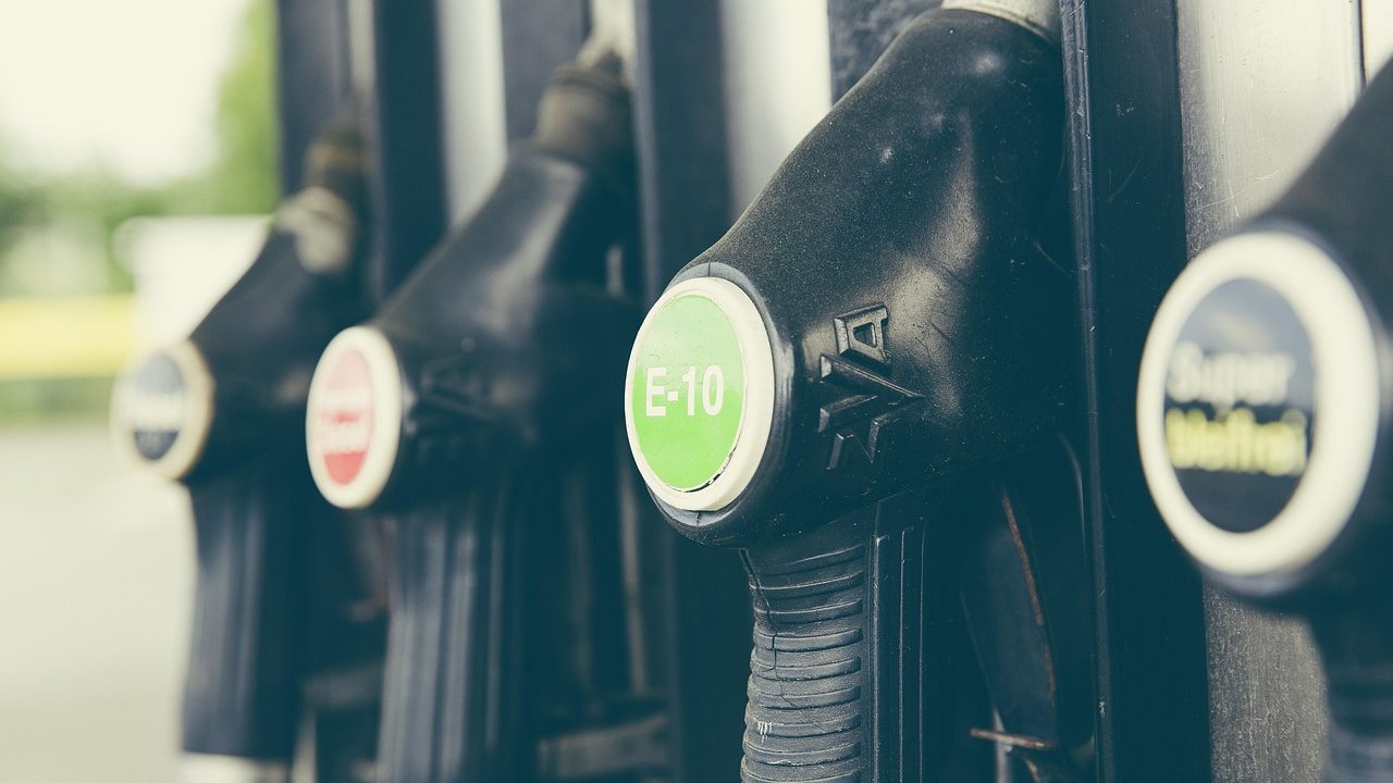 A row of fuel pumps at a gas station with a price sign visible above.