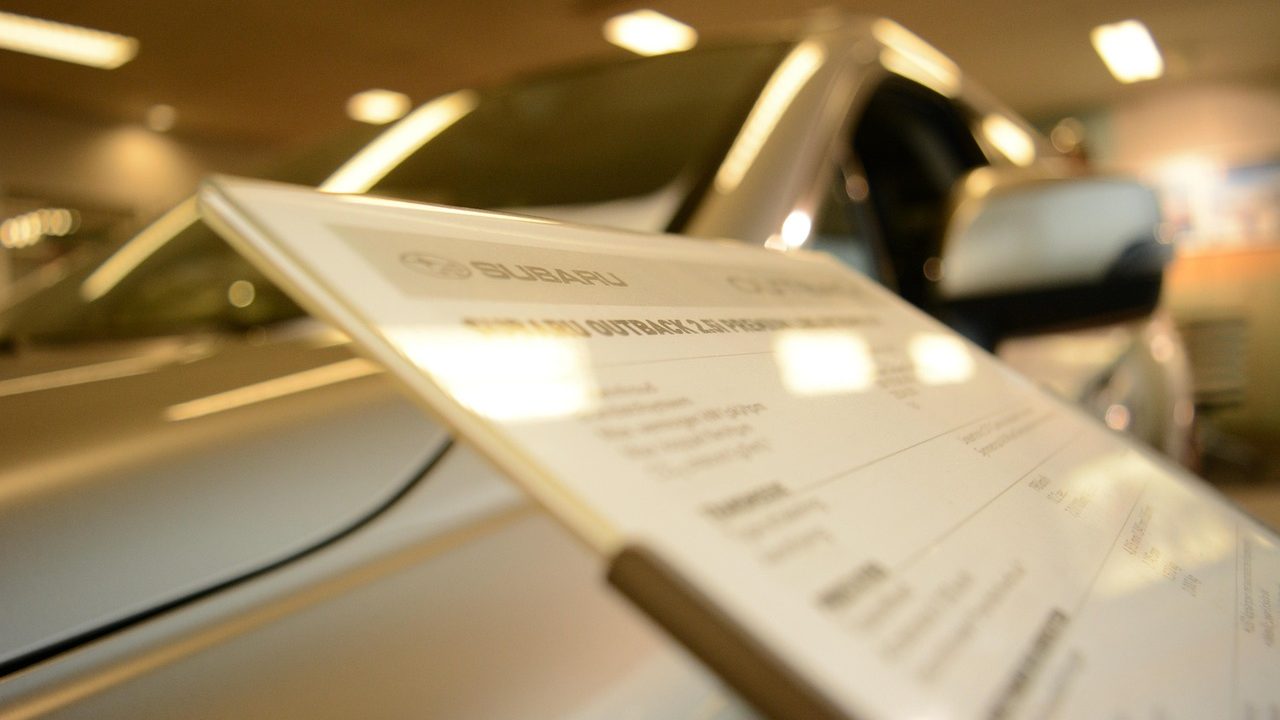 New vehicles lined up under bright lights on a dealership showroom floor.