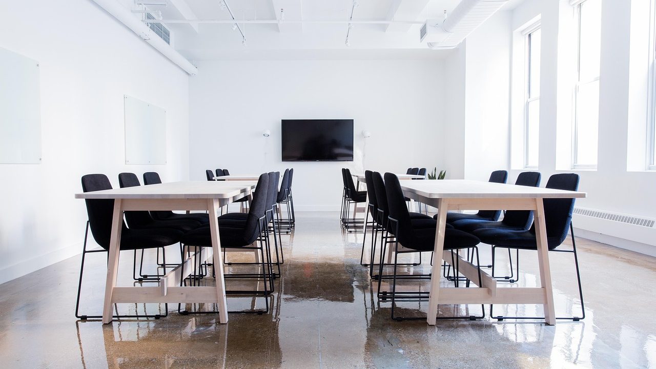 Empty leather chairs arranged around a long polished conference table in a formal meeting room.