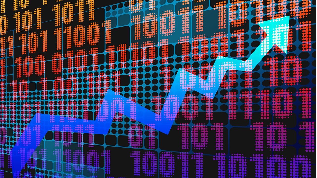 Traders on a busy stock exchange floor surrounded by electronic display boards showing market data.