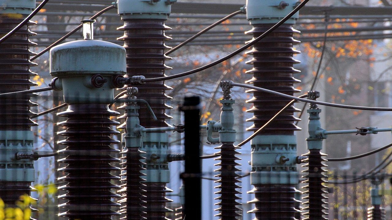 High-voltage electrical transformers and transmission lines at a large power substation.