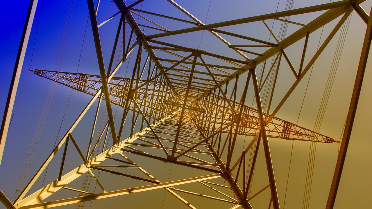 Rows of high-voltage transmission lines stretching across an open landscape at dusk.