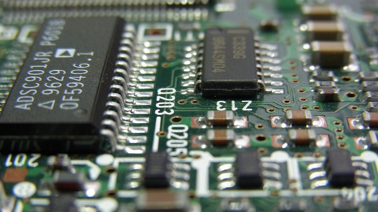 A macro photograph reveals the intricate copper traces and components of a green circuit board.