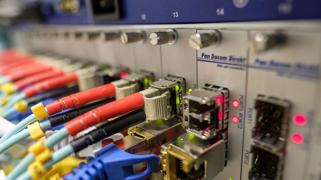 Bundles of illuminated fiber optic cables in a telecommunications infrastructure facility.