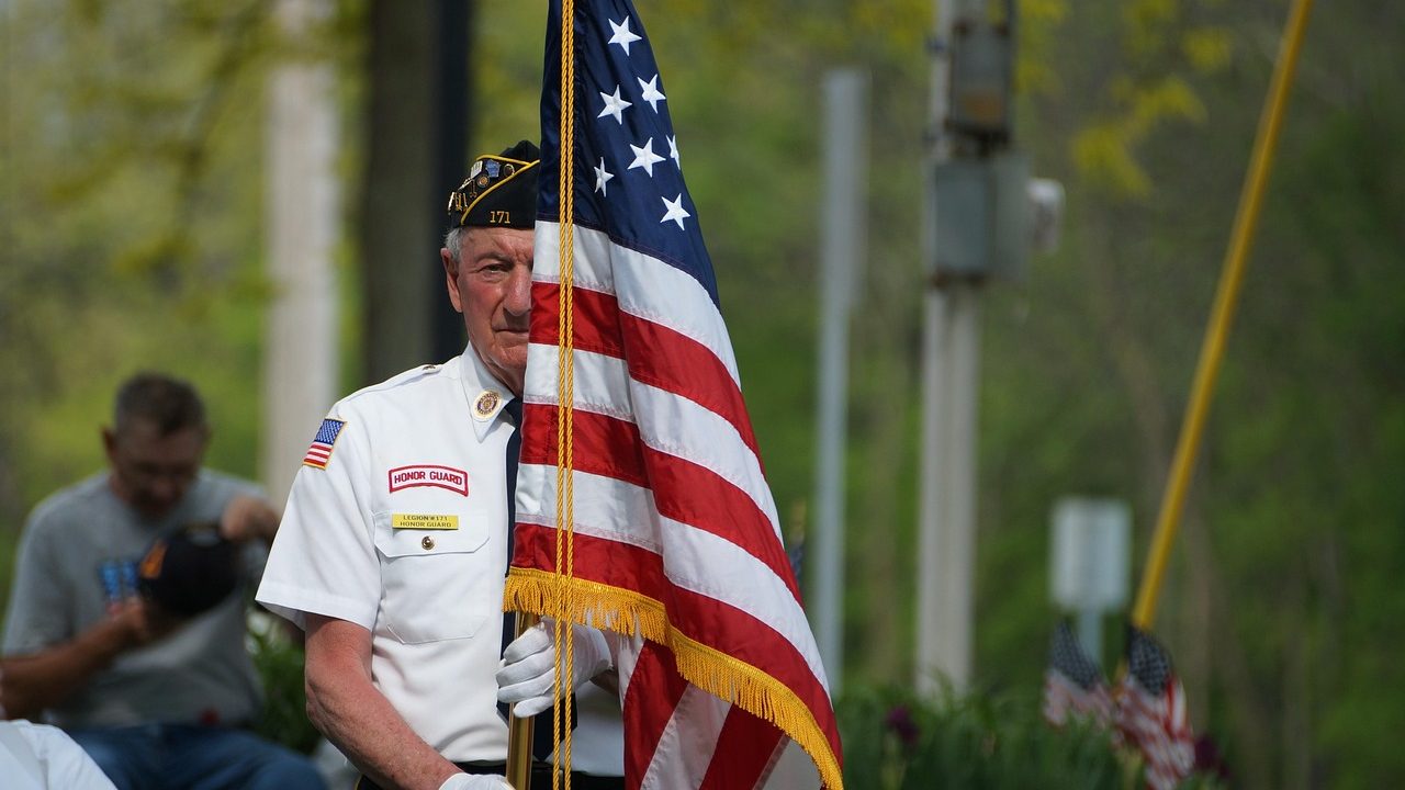 Rows of small American flags placed at a memorial site on a clear day.