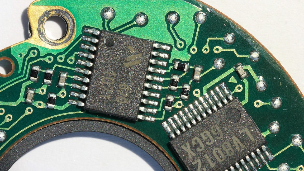 An extreme close-up of a green circuit board showing intricate copper traces and electronic components.